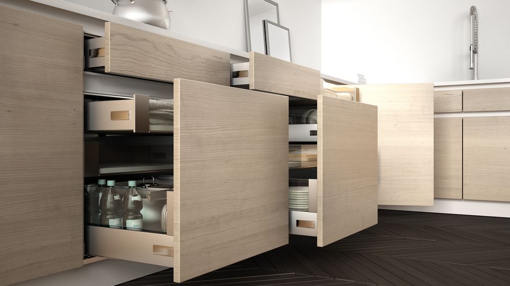 A pair of open kitchen cabinets along the lower end of a kitchen. You can see several spices and cooking supplies peeking out of the open drawers.