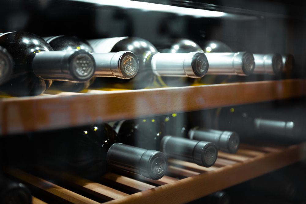 A close up image of a wine cooler with several bottles of wine inside.