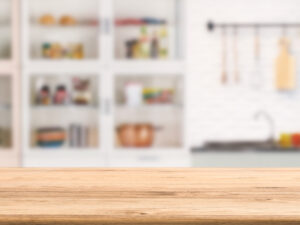 A wooden kitchen countertop with kitchen shelves blurred out in the background.