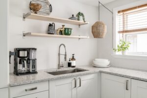 A close up of a white kitchen with open shelving elements