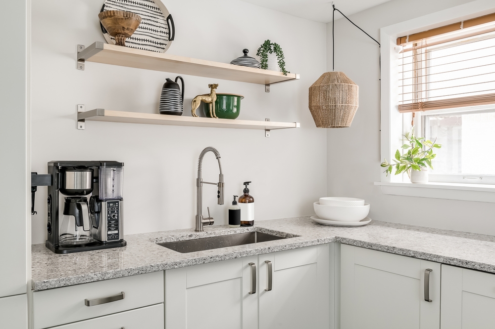 A close up of a white kitchen with open shelving elements